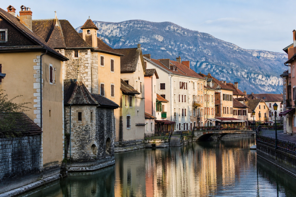 Canal and colorful historic buildings in Annecy, France, with the Alps in the distance